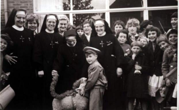 Groepsfoto op Koninginnedag 1961, op het schoolplein. Frank Bogers houdt hier een lammetje vast dat mee moest doen met de optocht. Helaas was het diertje de volgende dag van vermoeidheid gestorven.